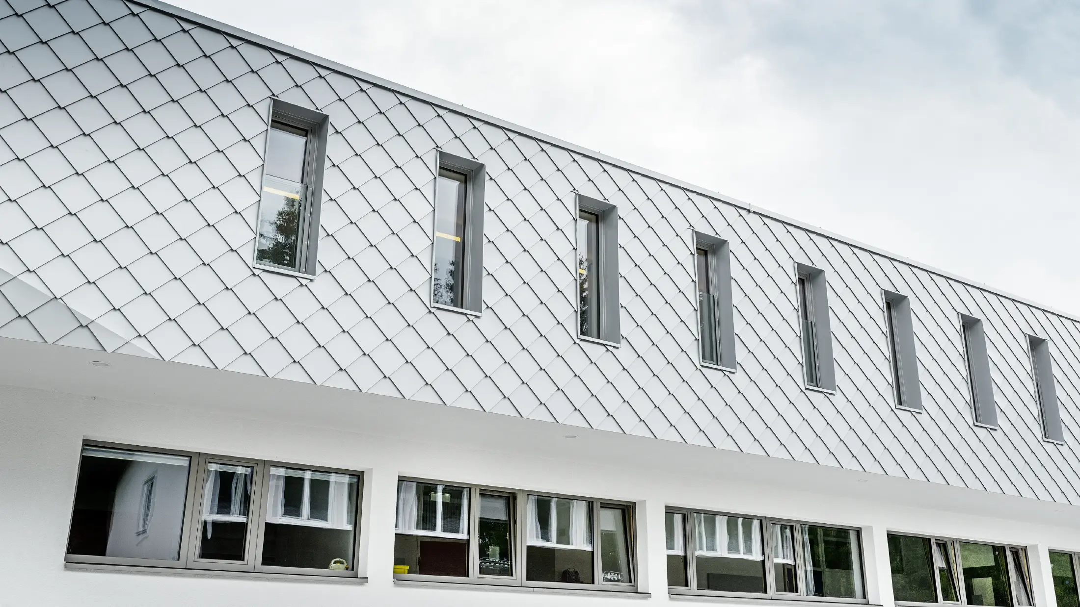 Novoizgrađeni vrtić u Kaprunu s modernom aluminijumskom fasadom obloženom PREFALZ zidnom rombom u Prefa bijeloj boji