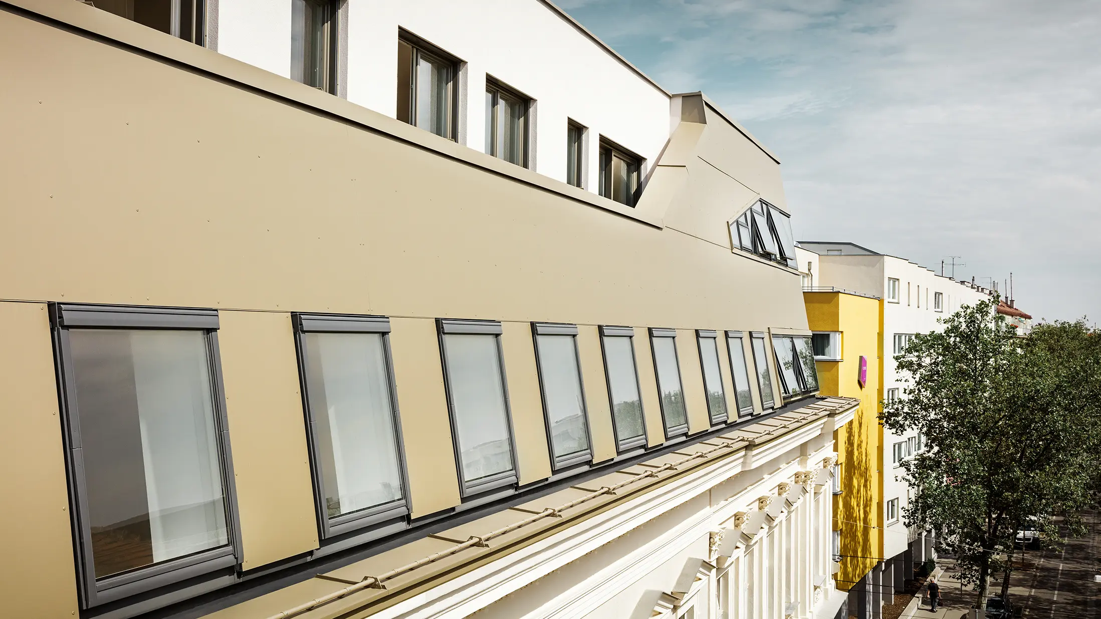 Bočni pogled na potkrovlje ističe ravnomjernu oblogu od PREFA aluminijumskih kompozitnih ploča u bronzanoj boji. Veliki prozori i široke staklene površine osiguravaju prostore ispunjene svjetlom i elegantan, moderan izgled.