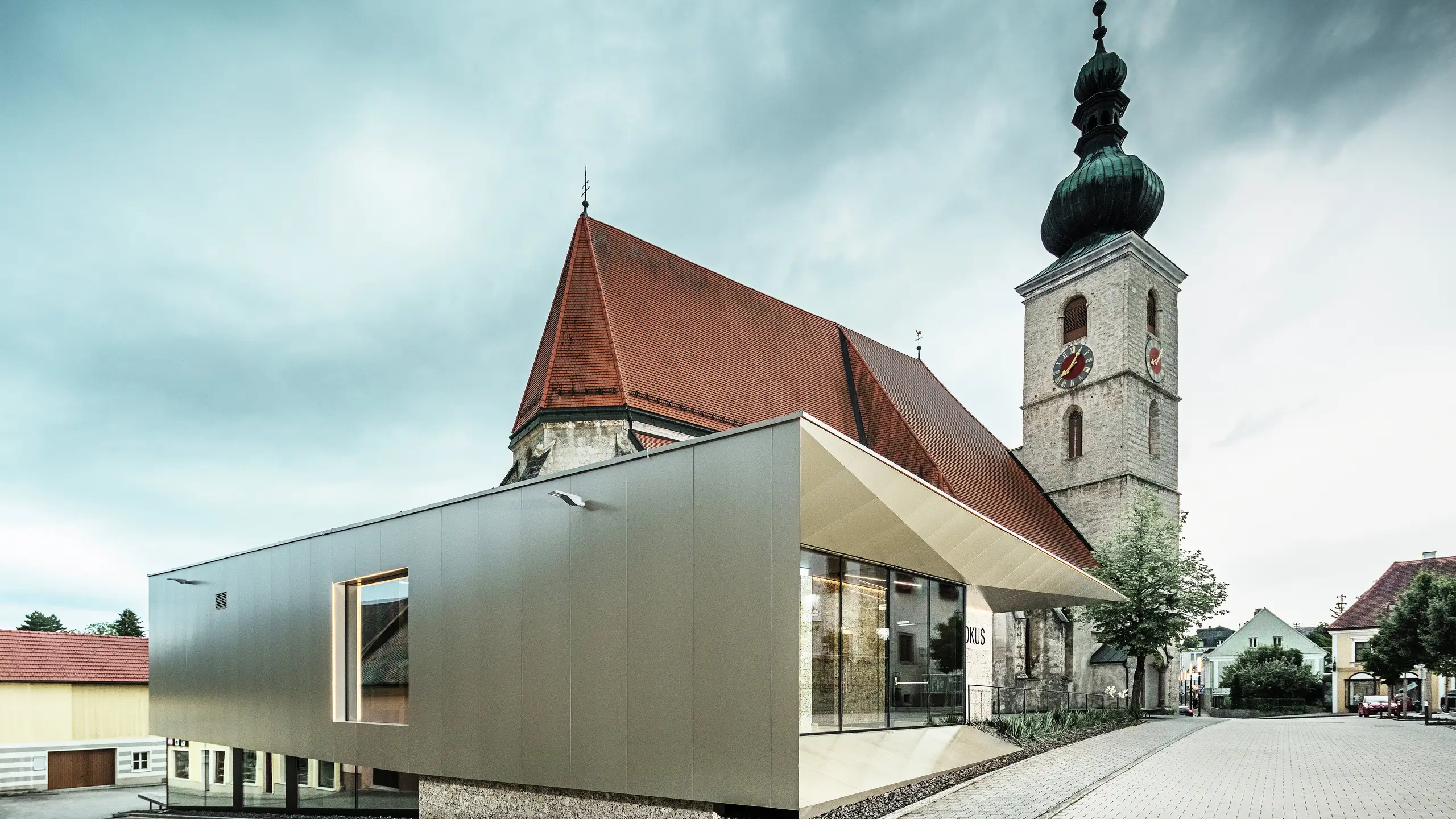 Die seitliche Ansicht zeigt den filigranen Dachüberstand, realisiert mit hochwertigen PREFA Aluminium Verbundplatten. Die exakte Verarbeitung ermöglicht eine moderne Optik mit klaren Linien und unterstreicht die architektonische Verbindung zwischen Alt und Neu.